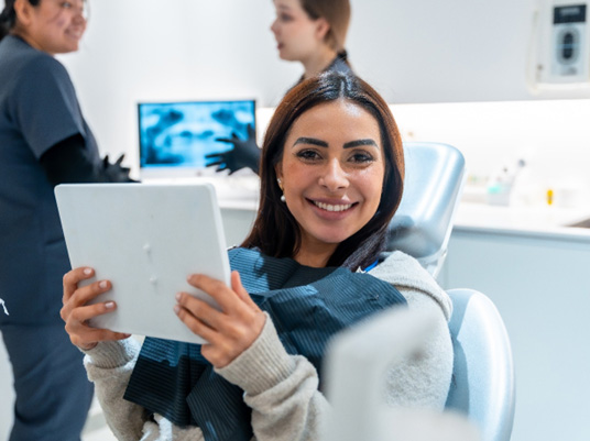 Woman smiling while holding handheld mirror