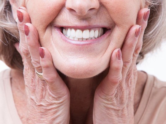 Close up of a woman’s smile while she touches her face