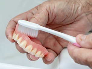 Man brushing his dentures