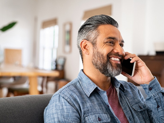 Man smiling while talking on phone at home