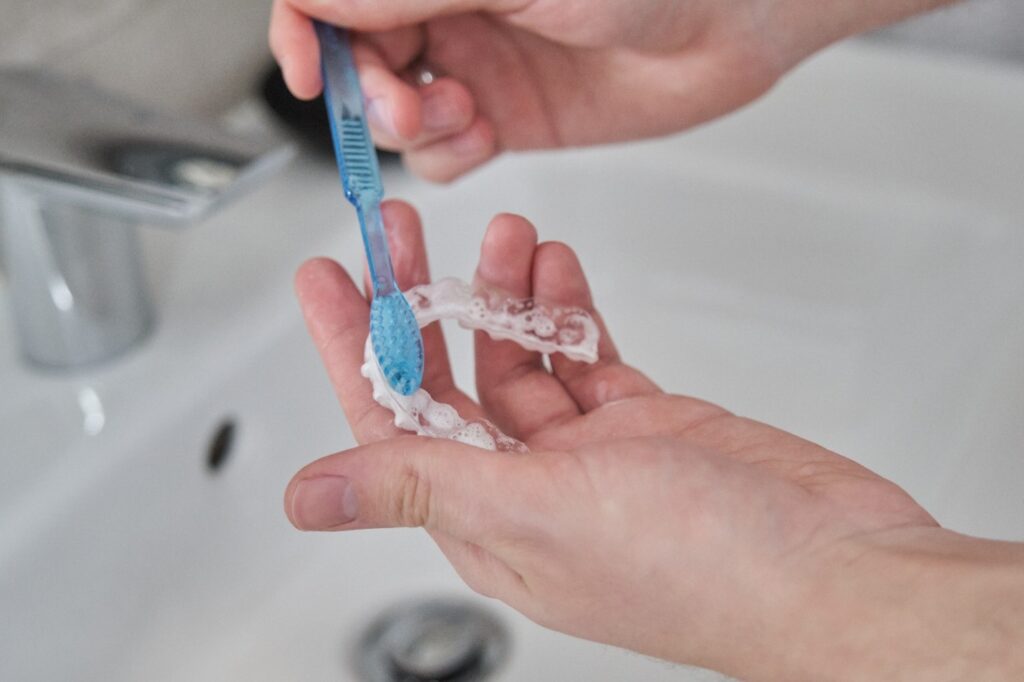 Patient using toothbrush to clean ClearCorrect aligner